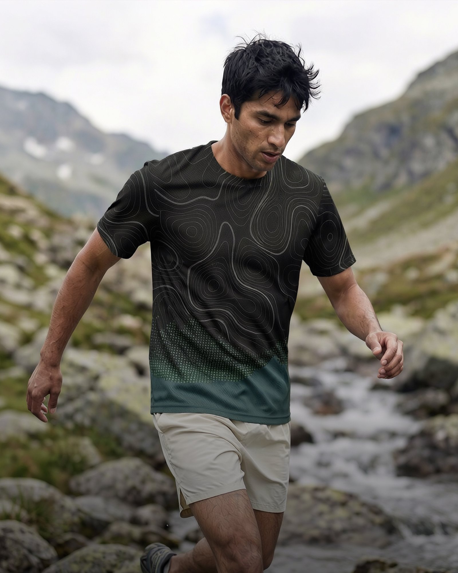 Runner in a topo-print tee crossing an alpine stream, made from a plain product photo